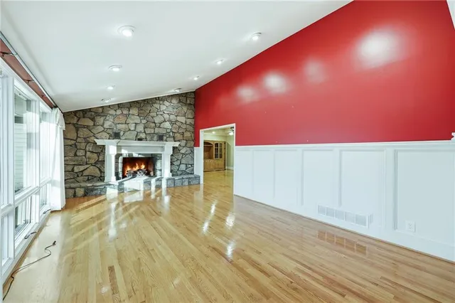 a view of an empty room with wooden floor and a ceiling fan