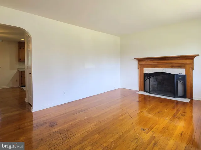 a view of empty room with wooden floor and fireplace