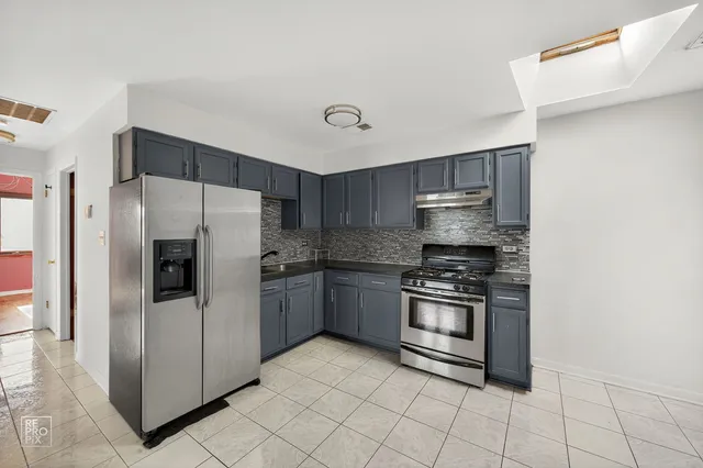 a kitchen with stainless steel appliances granite countertop a refrigerator and a stove top oven