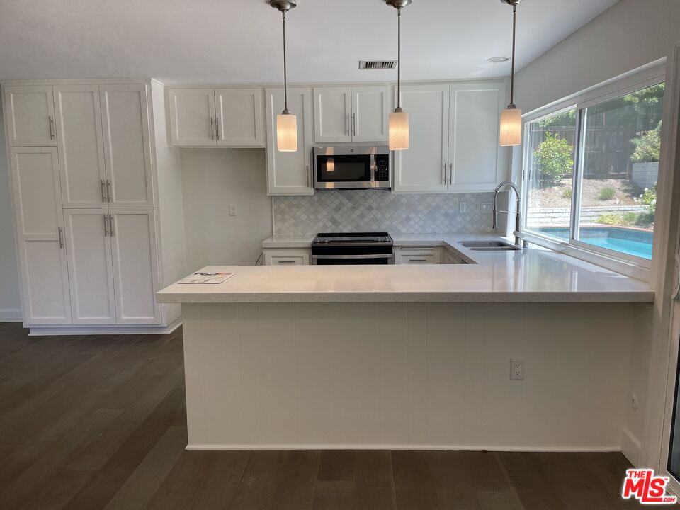 22634 Town Crier Road Calabasas, CA 91302 - Photo 3 of 7 a kitchen with stainless steel appliances granite countertop a sink a stove and a refrigerator