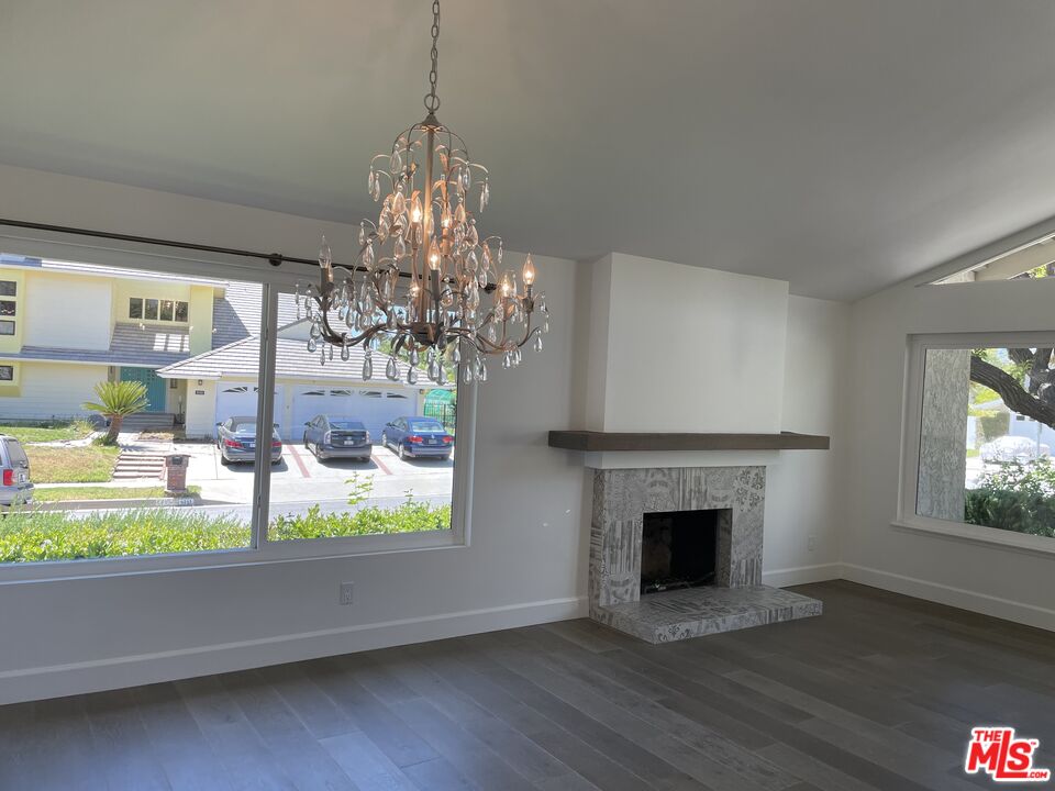 22634 Town Crier Road Calabasas, CA 91302 - Photo 4 of 7 a view of a livingroom with a fireplace a chandelier and windows