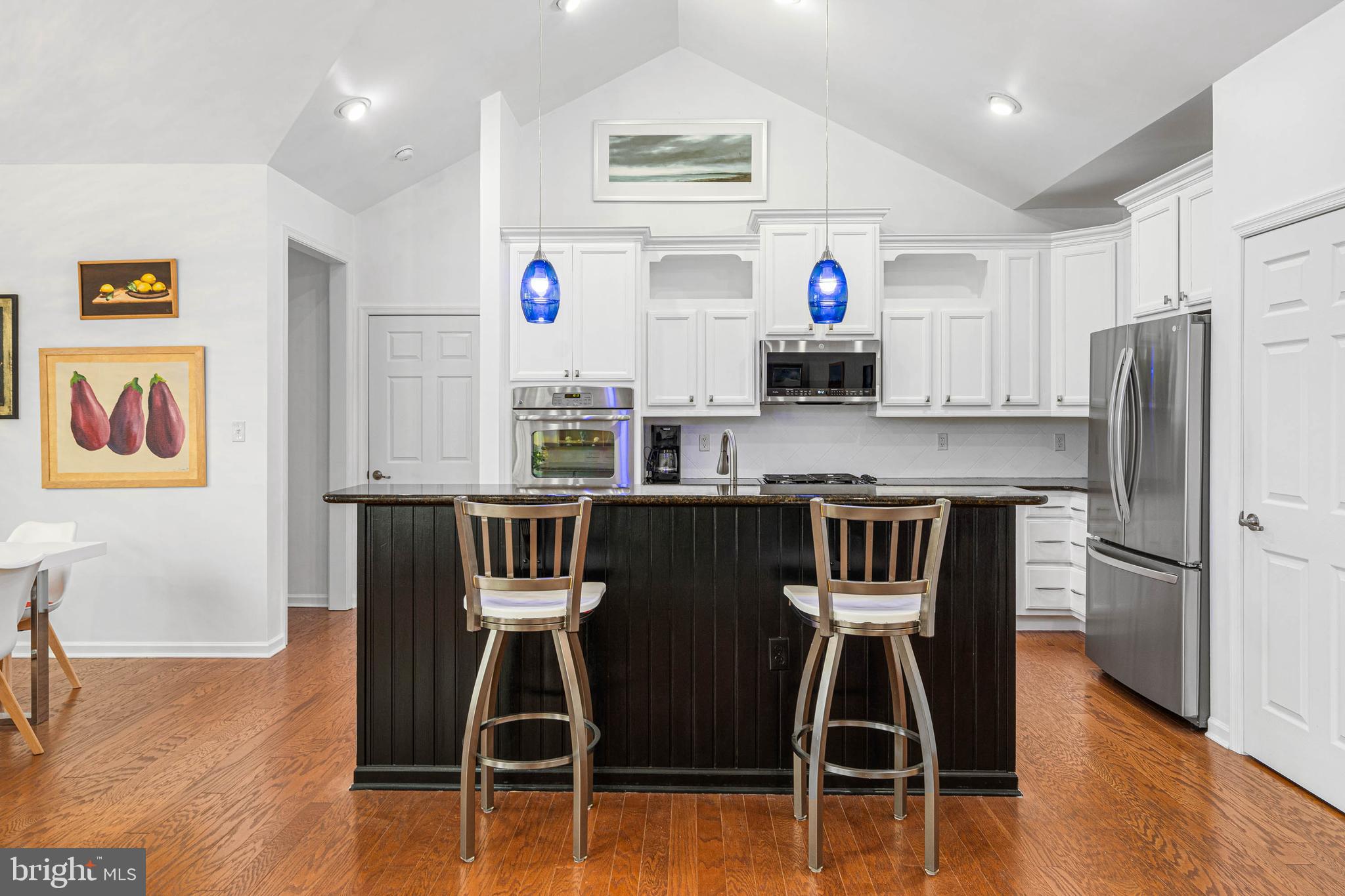 18923 Roth Drive Lewes, DE 19958 - Photo 21 of 73 a kitchen with stainless steel appliances granite countertop a stove top oven a refrigerator a dining table and chairs with wooden floor