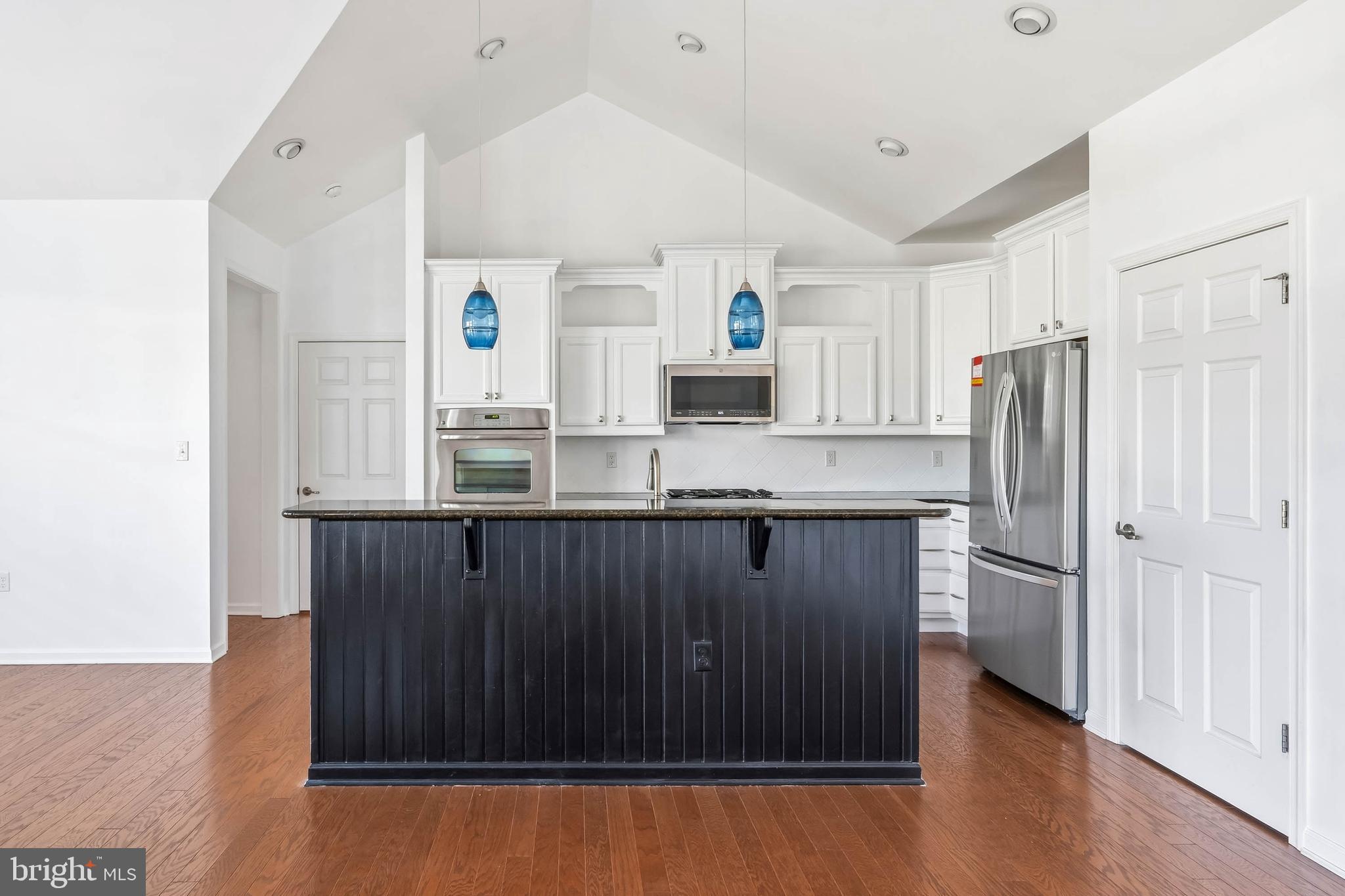18923 Roth Drive Lewes, DE 19958 - Photo 55 of 73 a kitchen with kitchen island granite countertop wooden cabinets and refrigerator