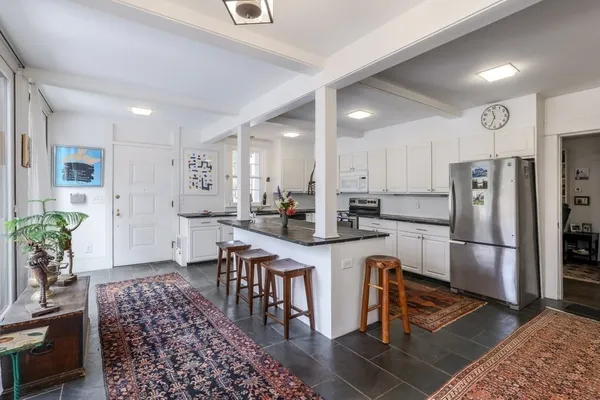 a kitchen with stainless steel appliances granite countertop a refrigerator a stove and a dining table with wooden floor