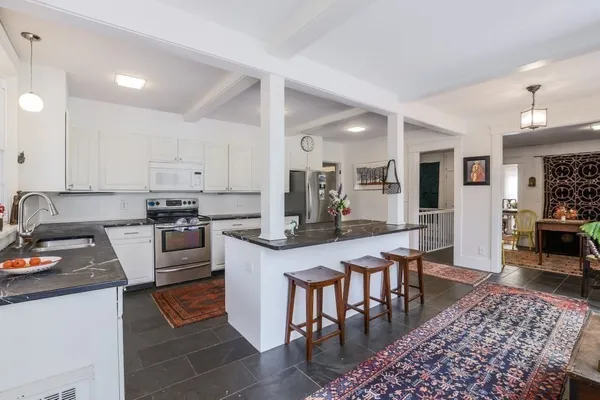 a kitchen with stainless steel appliances granite countertop a stove top oven a sink dishwasher a dining table and chairs with wooden floor