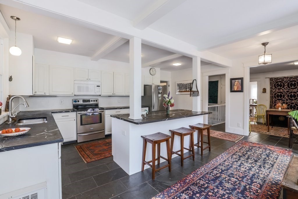 11 Ardlock Place Dudley, MA 01571 - Photo 33 of 42 a kitchen with stainless steel appliances granite countertop a stove top oven a sink dishwasher a dining table and chairs with wooden floor