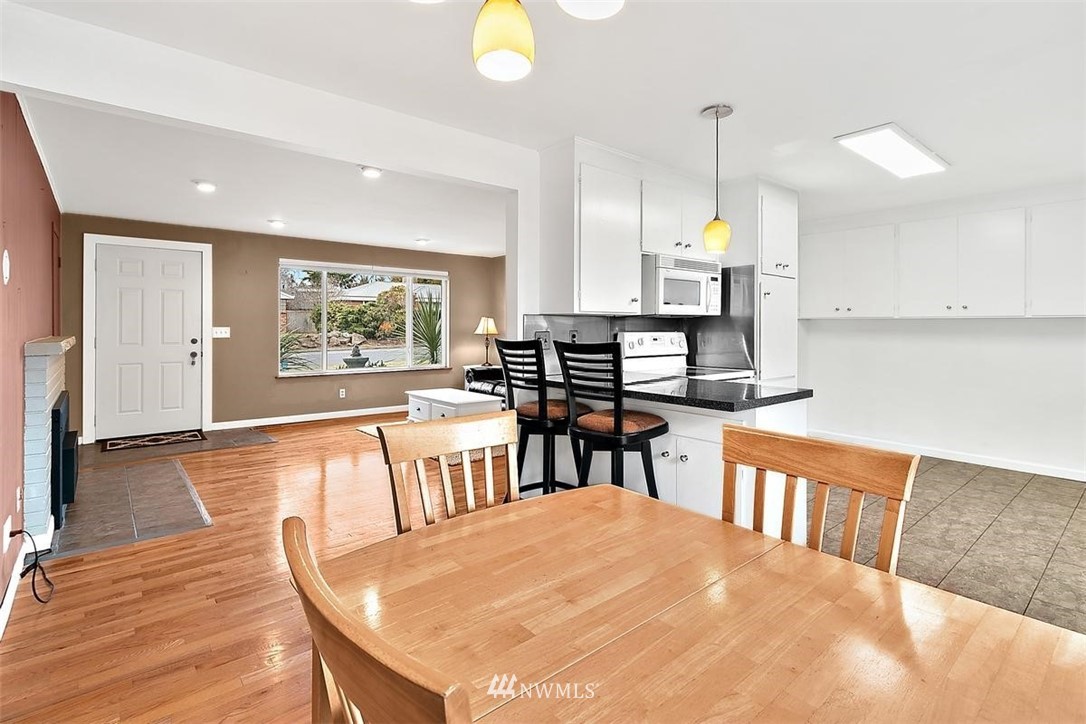 3407 Northeast 11th Street Renton, WA 98056 - Photo 8 of 27 a open kitchen with stainless steel appliances granite countertop a stove a refrigerator a dining table and chairs with wooden floor
