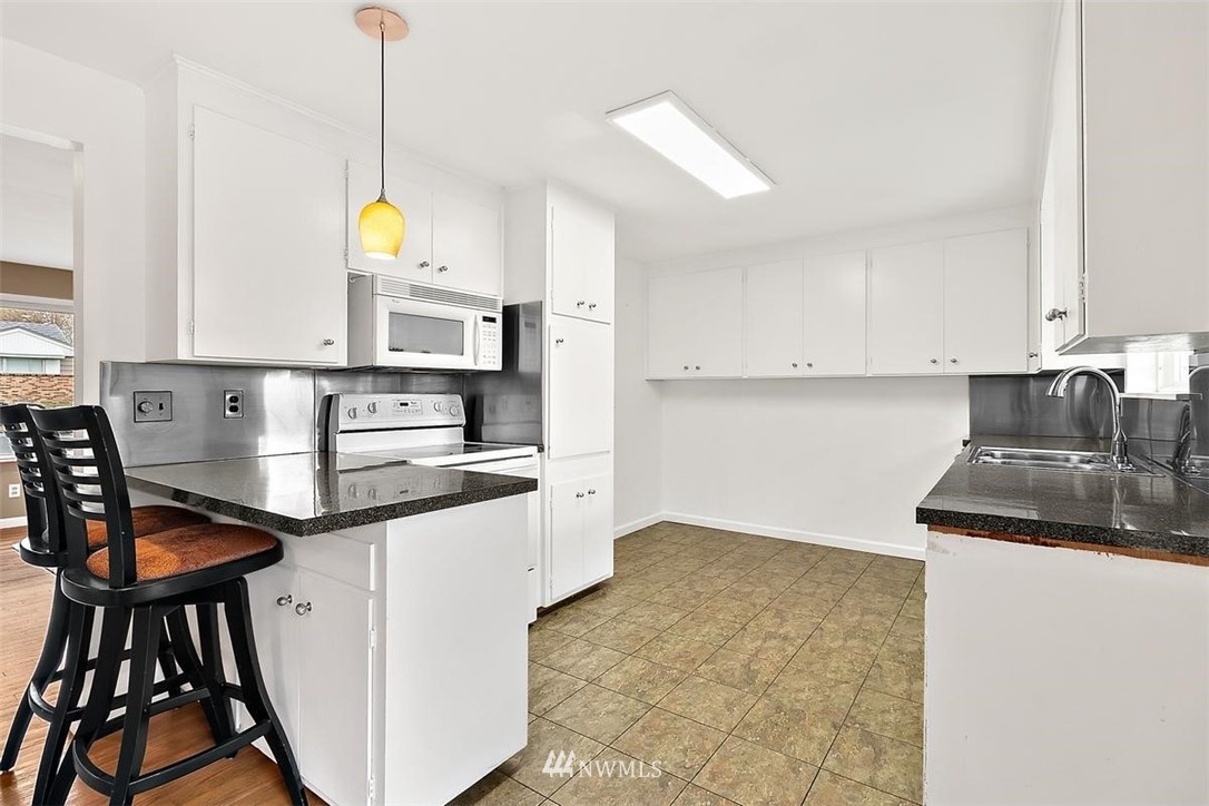 3407 Northeast 11th Street Renton, WA 98056 - Photo 9 of 27 a kitchen with stainless steel appliances granite countertop a sink a stove and a refrigerator