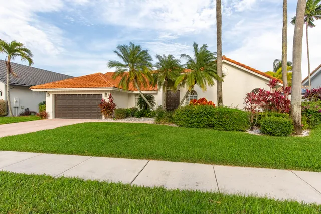 a front view of a house with a garden and palm trees