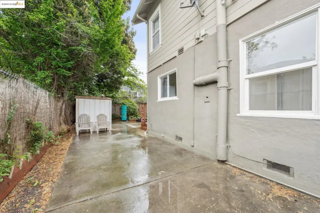 a backyard of a house with table and chairs and potted plants