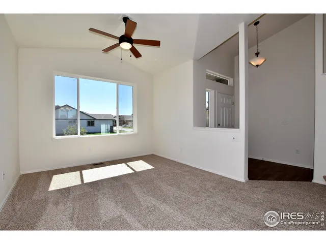 a view of an empty room with a ceiling fan and window