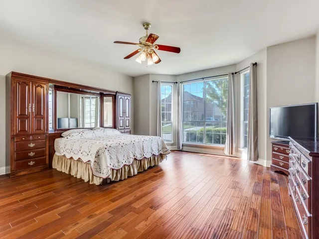 a spacious bedroom with a large bed and a flat tv screen