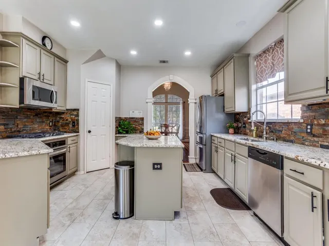 a kitchen with kitchen island granite countertop a stove top oven a sink dishwasher and a refrigerator
