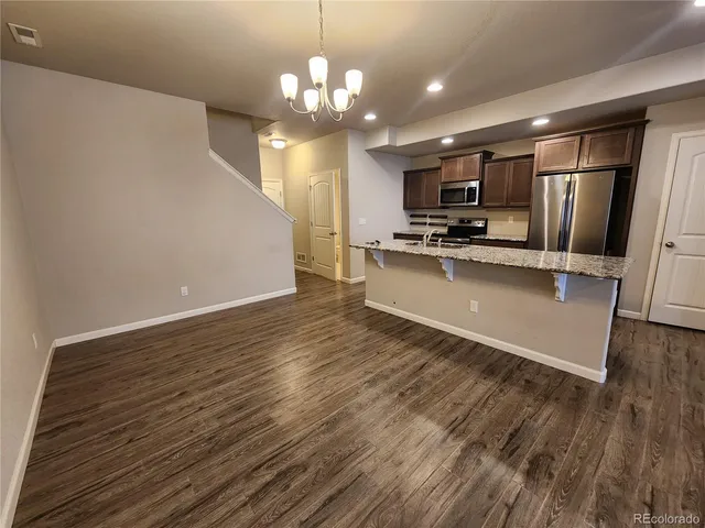 a large kitchen with stainless steel appliances a large counter top a stove and a refrigerator