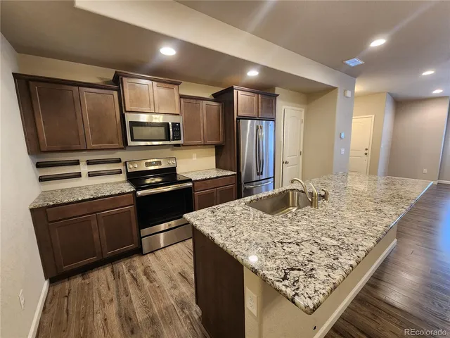 a kitchen with stainless steel appliances kitchen island granite countertop wood cabinets and granite counter tops