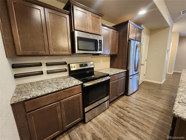 a kitchen with stainless steel appliances granite countertop a stove a microwave and a refrigerator
