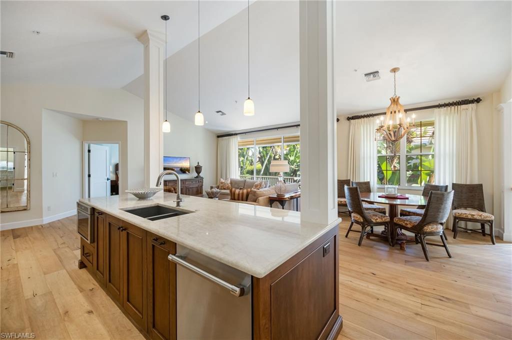 611 10th Avenue South, Unit B2 Naples, FL 34102 - Photo 10 of 27 Kitchen featuring decorative light fixtures, light wood-style floors, vaulted ceiling, light stone countertops, and appliances with stainless steel finishes