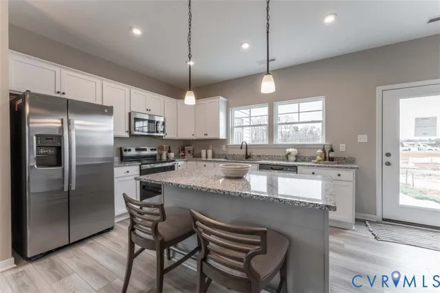 a large kitchen with a center island wooden floor stainless steel appliances and windows