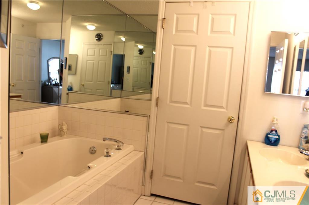 98 Prestwick Way Edison, NJ 08820 - Photo 14 of 16 a bathroom with a tub a sink and a large mirror