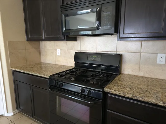 a kitchen with granite countertop a stove and a microwave