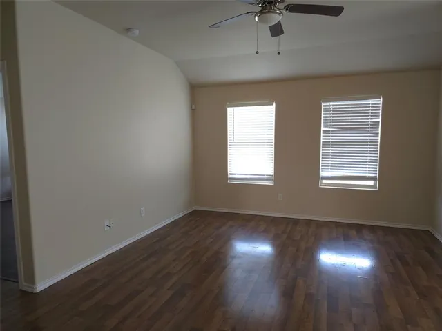 an empty room with wooden floor fan and windows