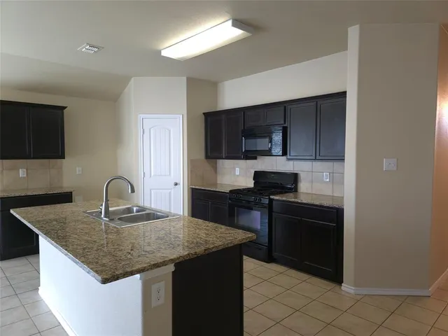 a kitchen with granite countertop a stove sink and microwave
