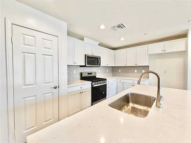 a kitchen with granite countertop a sink a counter top space stainless steel appliances and cabinets