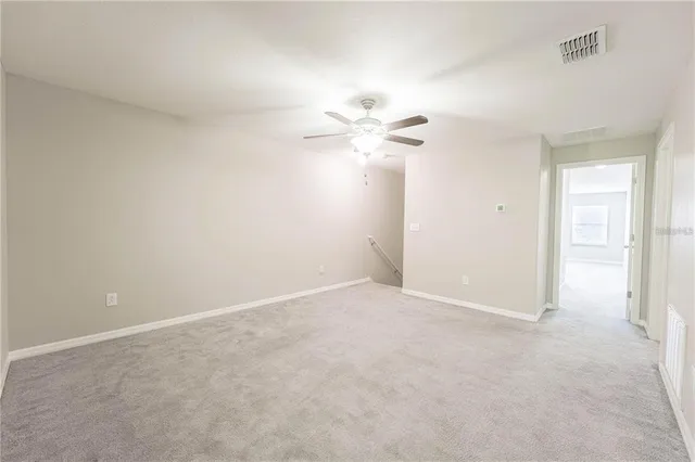 an empty room with a chandelier fan and windows
