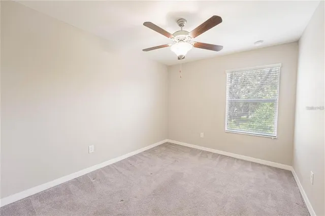 an empty room with a window and a fan