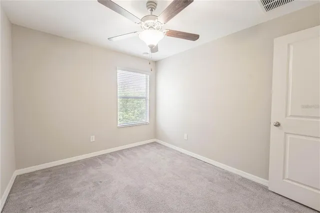 an empty room with a window and a fan