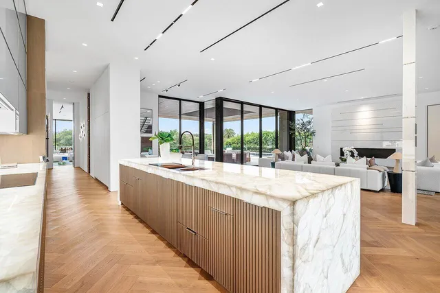 a large kitchen with kitchen island a stove a sink dishwasher and a dining table with wooden floor