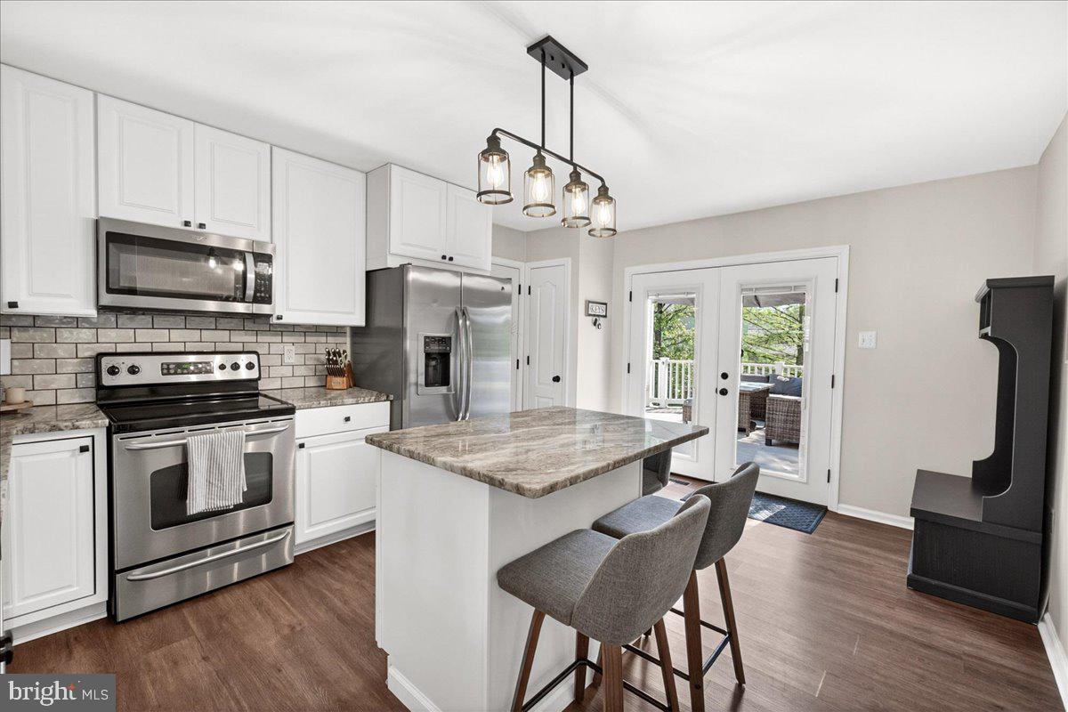 98 Pleasanton Court Frederick, MD 21702 - Photo 11 of 62 a kitchen with stainless steel appliances granite countertop a stove top oven a sink dishwasher a dining table and chairs with wooden floor