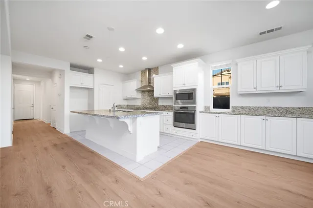 a large kitchen with kitchen island a sink a stove a refrigerator and white cabinets