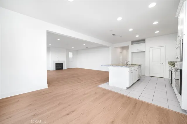 a view of a kitchen with kitchen island wooden floors appliances and a sink