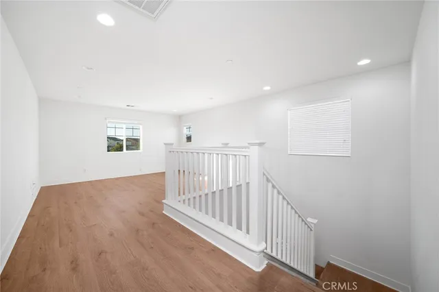 a view of a hallway with wooden floor and windows
