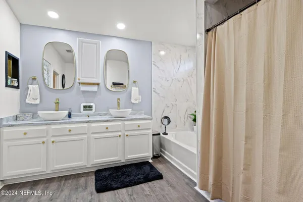 a spacious bathroom with a double vanity sink a mirror and a bathtub