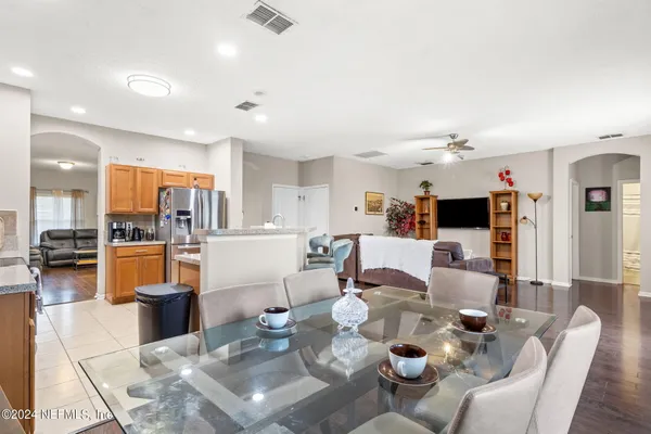 a living room with furniture kitchen view and a wooden floor