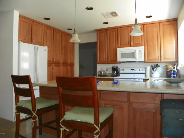 a kitchen with stainless steel appliances granite countertop a table chairs and a refrigerator