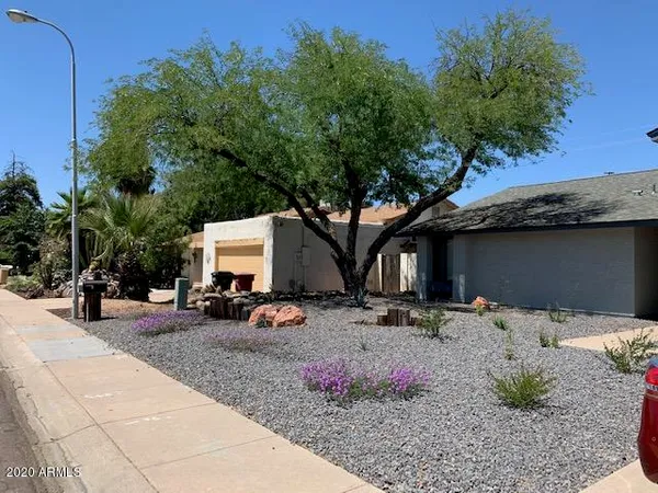 a backyard of a house with table and chairs under an umbrella
