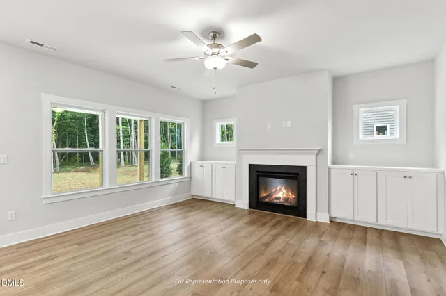 a view of an empty room with wooden floor fireplace and a window