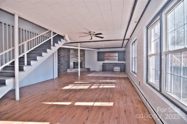 a view of an empty room with chandelier fan and wooden floor
