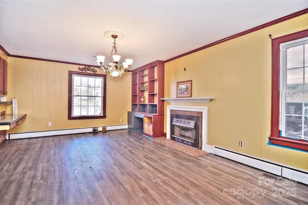 an empty room with wooden floor fireplace and windows