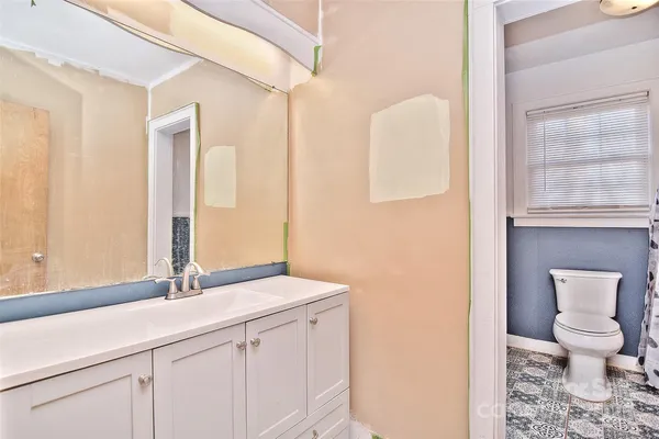 a bathroom with a granite countertop sink a toilet and a mirror