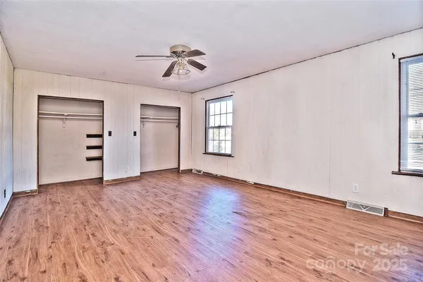 a view of an empty room with a window and wooden floor