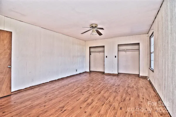 a view of empty room with wooden floor and fan