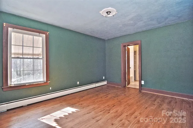 a view of an empty room with window and wooden floor