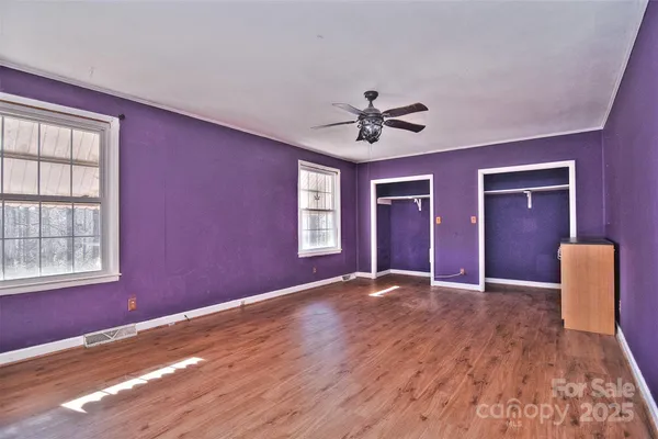 a view of an empty room with window and wooden floor