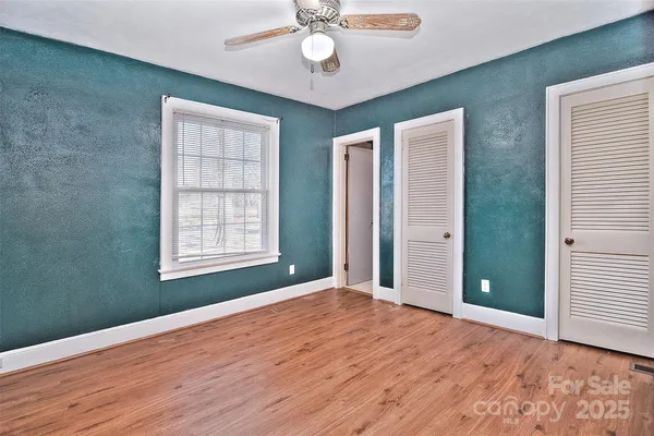 a view of an empty room with window and wooden floor