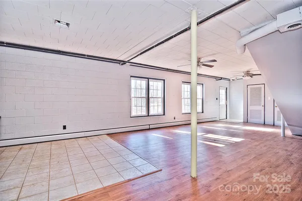 a view of an empty room with window and wooden floor