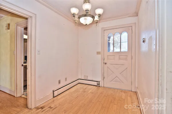 a view of an empty room with chandelier fan and wooden floor